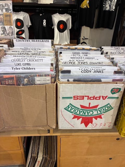 A table covered in boxes filled with country music albums on vinyl.