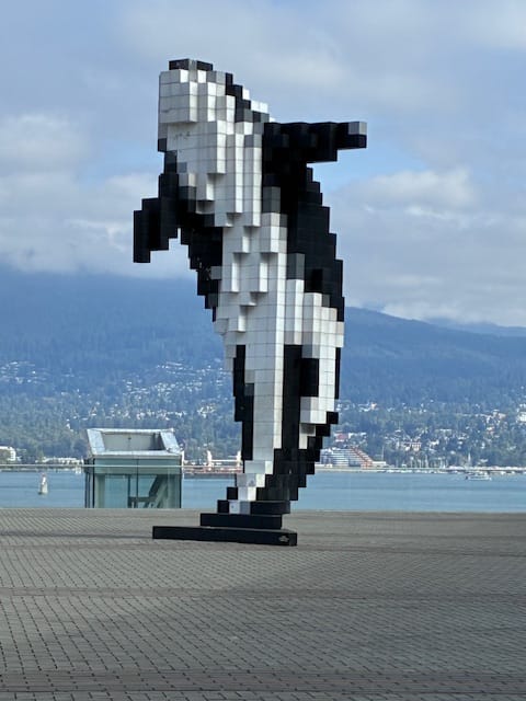 A pixelated black and white statue of a killer whale on the Vancouver waterfront.